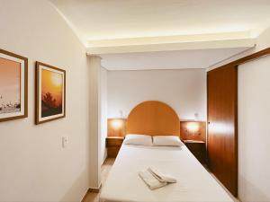 a bedroom with a white bed with a wooden headboard at Babitonga Hostel - 100m da Prainha in São Francisco do Sul