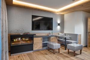 uma sala de estar com lareira e televisão em Hotel Alpina Wellness & Spa Resort em Kössen