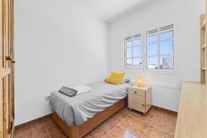 ein weißes Schlafzimmer mit einem Bett und einem Fenster in der Unterkunft Casa Merlin in Playa Honda
