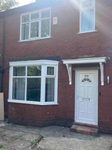 a brick house with a white door and windows at Newly Renovated 3- Bed house in Prestwich in Manchester