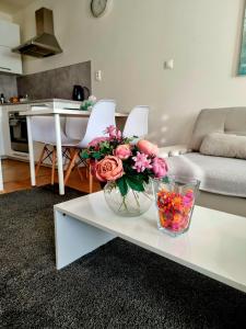 Una mesa de café blanca con un jarrón de flores. en Apartment Banska - City Centre & Free Parking, en Banská Bystrica