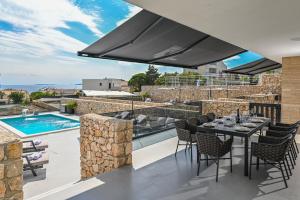 an outdoor patio with a table and chairs and a pool at Luxury Villas Great Escape & Noa in Novalja