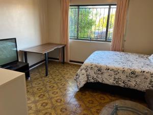 1 dormitorio con cama, mesa y TV en Aspley bedroom & share bathroom with other guests, en Brisbane