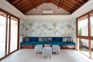 a living room with a blue couch and palm trees wallpaper at Poco Poco villas by Aayan in Jimbaran