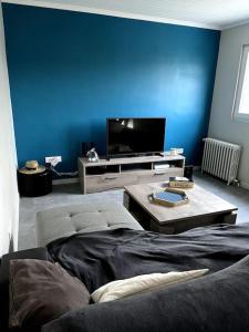 a living room with a blue wall and a tv at Maison avec jardin in Venizel