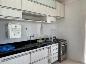 cocina blanca con fregadero y fogones en Reluz Tranquility melhorcasaaracaju, en Aracaju