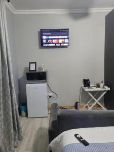 ein Wohnzimmer mit einem Sofa und einem TV an der Wand in der Unterkunft Ayana bnb in Bloemfontein