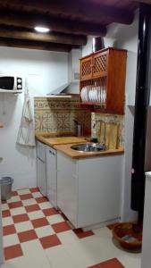 a small kitchen with a sink and a checkered floor at Mi Casita - Higuera de la Sierra in Higuera de la Sierra