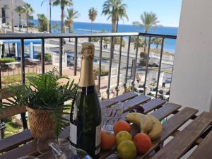 a bottle of champagne sitting on a wooden table with fruit at Spacious Front Line Beach 3 Bedroom apartment with amazing sea views a few steps from the beach in Benalmádena