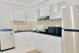 a kitchen with white cabinets and a refrigerator at Joansa Luxury Beachfront Apartment in Uswetakeiyawa