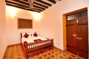 a bedroom with a bed with a wooden door at Villa D Jems -A Heritage Home stay in Puducherry
