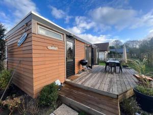 una casa pequeña con terraza de madera con parrilla en Moderne bungalow voor 6 personen, en Julianadorp