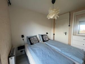 1 dormitorio con cama con sábanas azules y ventana en Moderne bungalow voor 6 personen, en Julianadorp