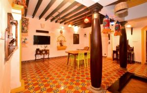 Villa D Jems -A Heritage Home stay في بونديتْشيري: غرفة معيشة مع طاولة وتلفزيون على الحائط