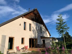 een huis met stoelen en een tafel aan de zijkant bij Ferme de la Croix Blanche, Vercors (4 ch, 8 pers) in Méaudre