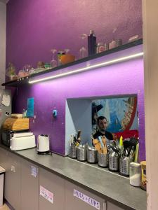 Un homme dans une cuisine avec un mur violet dans l'établissement Carpe Noctem Hostel, à Budapest