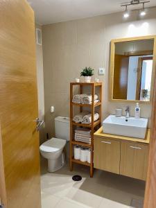 y baño con lavabo, aseo y espejo. en Two bedroom Apt., Hacienda Riquelme Golf Resort en Murcia