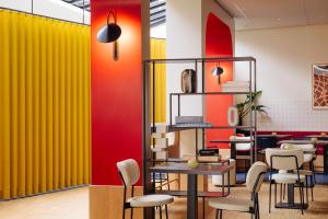 a restaurant with yellow and red walls and chairs at City Hotel Groningen in Groningen