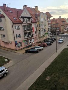 a row of cars parked on a street with buildings at Apartament Słoneczny Olecko Centrum in Olecko