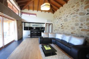 a living room with a black couch and a stone wall at Villa 251 in Barcelos
