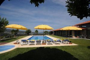 a pool with chairs and umbrellas next to a house at Villa 251 in Barcelos
