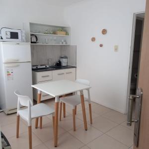 a white kitchen with a white table and chairs at Dpto Estudio in Gualeguaychú