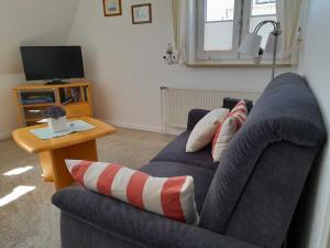 een woonkamer met een blauwe bank en een televisie bij Gästehaus "Gorch Fock" in Wyk auf Föhr