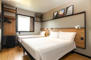 um quarto de hotel com duas camas e uma janela em ibis Porto Alegre Aeroporto em Porto Alegre