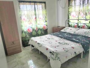 1 dormitorio con 1 cama con colcha de flores en DeiHouse, en Samal