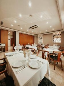 une salle à manger avec des tables et des chaises blanches dans l'établissement Hoteles Urbanos N Avenida de España, à Fuenlabrada