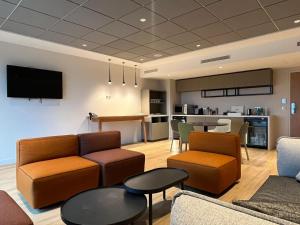 a living room with couches and chairs and a kitchen at Holiday Inn Paris CDG Airport an IHG Hotel in Roissy-en-France