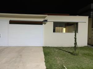 Casa com piscina em condomínio في كاشويرا باوليستا: كراج ابيض بباب ونافذة