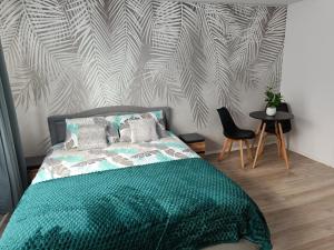 a bedroom with a bed with a green comforter at Apartamenty Centrum- Wojska Polskiego in Słupsk