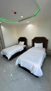 duas camas com lençóis brancos num quarto em برج موجان السكني التجاري em Khamis Mushayt