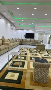 Habitación con sofás, mesa y pantalla. en برج موجان السكني التجاري, en Khamis Mushayt