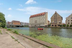 een rivier met gebouwen en een rode boot in het water bij Apartament z widokiem na rzekę by Grand Apartments in Gdańsk