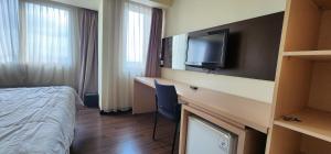 a hotel room with a bed and a desk with a television at Apartemen Solo Paragon by Cariapartemen-id in Bonorejo