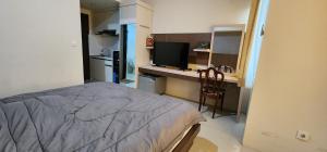 a bedroom with a bed and a desk with a television at Apartemen Solo Paragon by Cariapartemen-id in Bonorejo