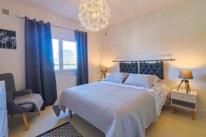um quarto com uma cama com cortinas azuis e um lustre em Maison sur la route du Cognac em Saint-Même-les-Carrières
