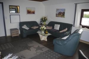 - un salon avec deux canapés en cuir et une table dans l'établissement Ferienhaus Mitteldeich, à Butjadingen