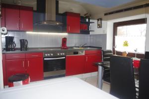 een keuken met rode kasten en een fornuis met oven bij Ferienhaus Mitteldeich in Butjadingen