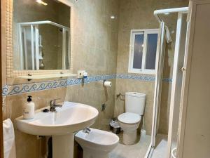 een badkamer met een wastafel, een toilet en een spiegel bij Apartamento Almogávares in Córdoba