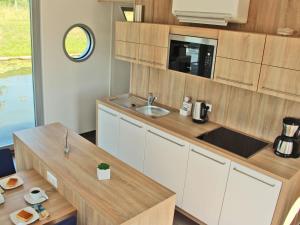 a small kitchen with white cabinets and a sink at Hausboot Ueckermuende in Ueckermünde