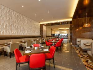 a restaurant with red chairs and tables in a room at Flora Al Barsha Hotel At The Mall in Dubai