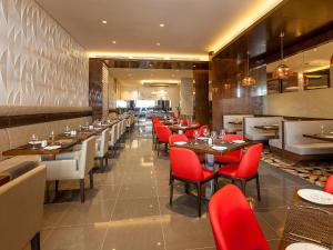 a dining room with tables and red chairs at Flora Al Barsha Hotel At The Mall in Dubai