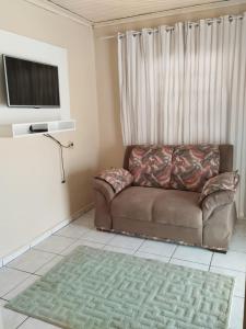 ein Wohnzimmer mit einem Sofa und einem TV in der Unterkunft RECANTO DA IZAURINHA in Olímpia