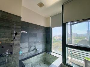 La salle de bains est pourvue d'une baignoire, d'une douche et d'une fenêtre. dans l'établissement Now and Then Hot Spring Inn, à Jiaoxi
