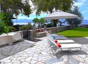 Karaḯskos的住宿－Beachfront Skaloma Villa，庭院设有2把躺椅和遮阳伞