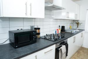 a kitchen with a black microwave and a stove at Large Ideal Accommodation for Groups & Contractors in Horsforth