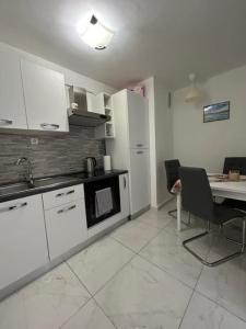 een keuken met witte kasten, een bureau en een tafel met stoelen bij Apartment ZORA in Knin